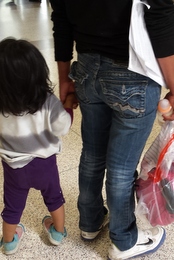 A mom and daughter wait in line at a bus station.