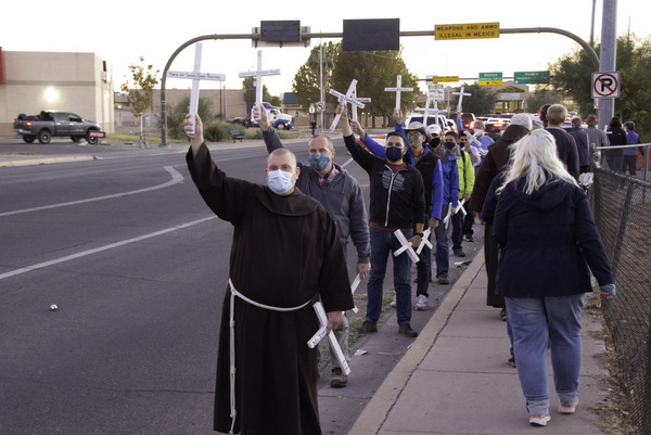 friar and crowd hold up white crosses