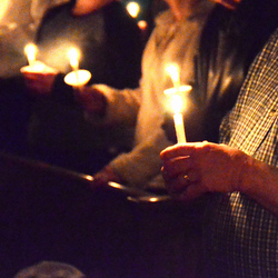 people holding candles in dark