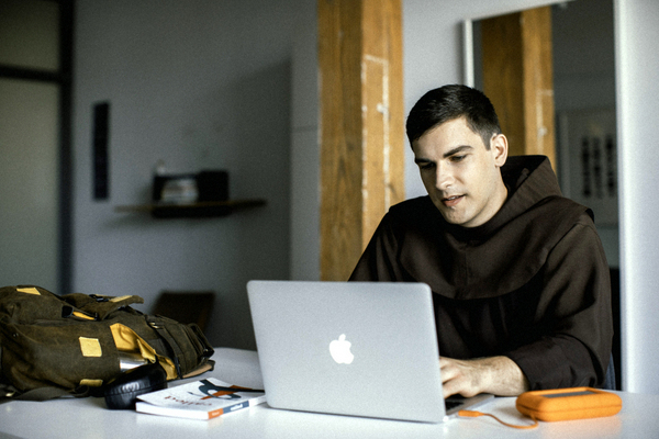 Friar in habit with laptop