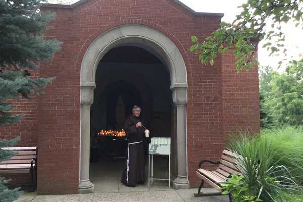 Br. Norbert Bertram lights a candle at the entrance to the outdoor grotto at the Shrine