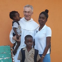 friar holds a baby with a family