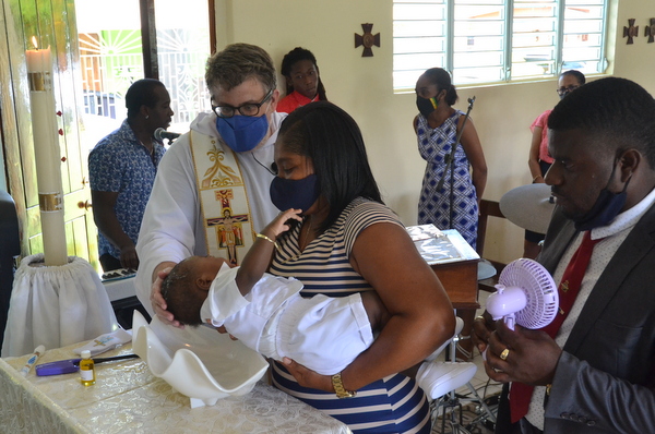 friar baptizing baby with parents