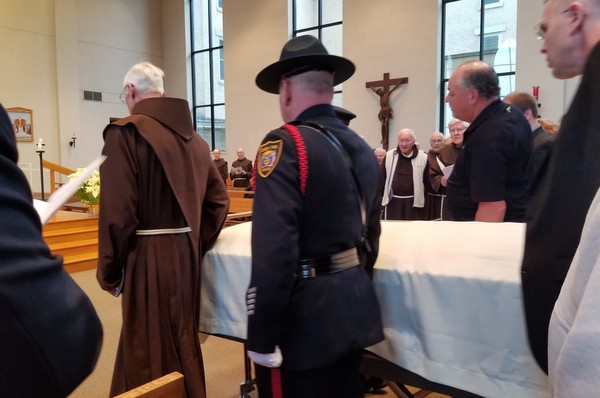 police and friars with casket