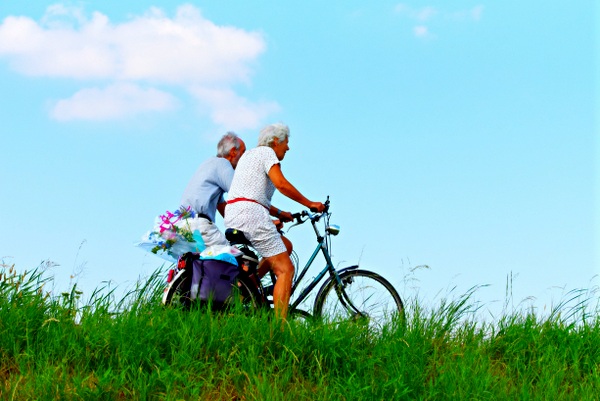 couple biking near grass and blue sky