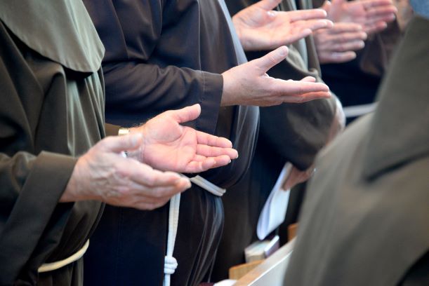 Friars with hands extended in prayer