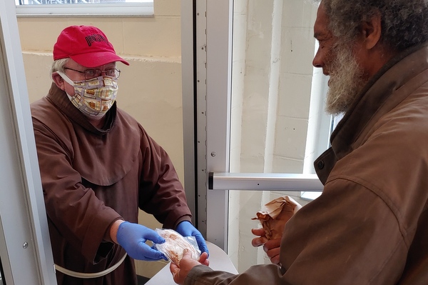 Br. Bill gives food to a client