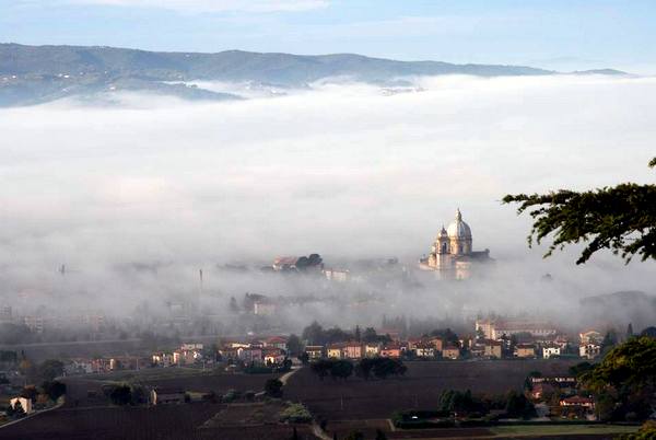 Peaking through the fog sits Santa Maria de Angeles in the valley below Assisi, Italy. The tiny Portiuncula ("little portion") lives inside.