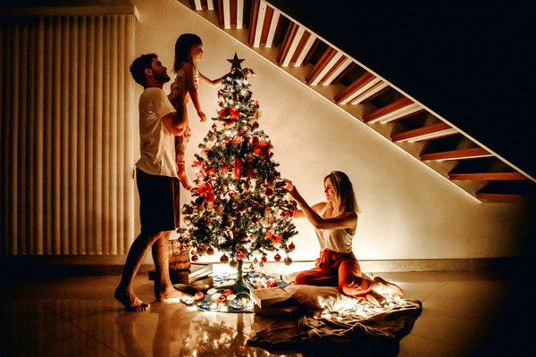 couple and baby trimming Christmas tree