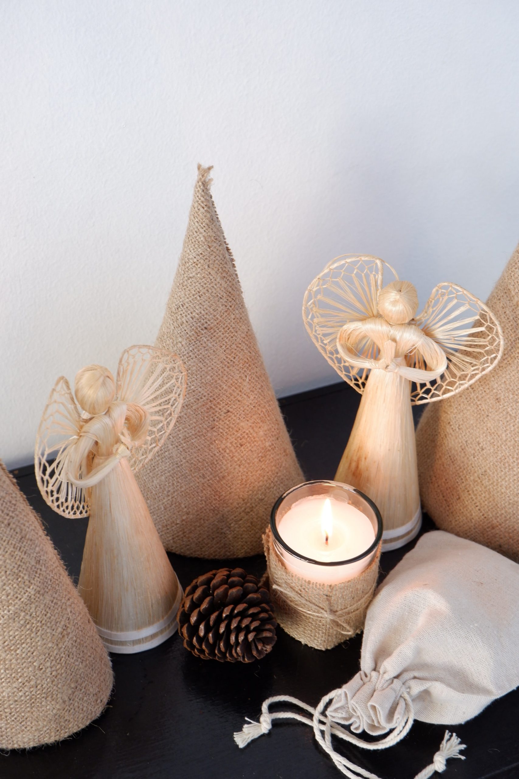 A Christmas scene with angels, a pinecone, and a candle